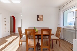 Un coin repas avec une table et des chaises en bois, un tableau accroché au mur et une vue par la fenêtre.
