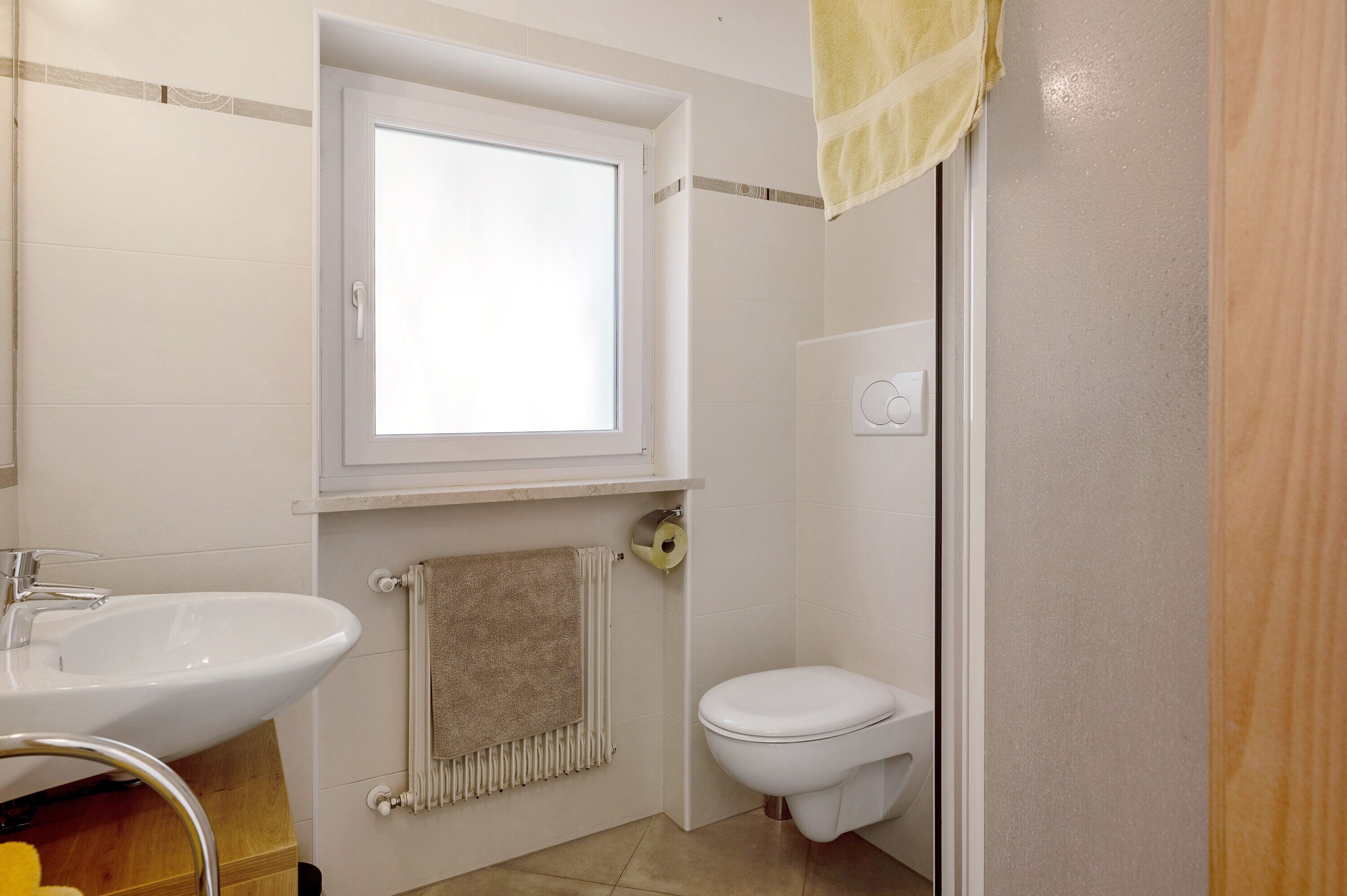 A bathroom with a sink, toilet, and window.