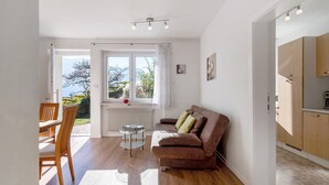 Sala de estar com sofá, mesa de jantar e vista para o exterior.