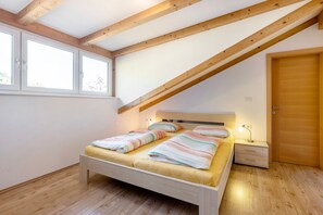 Un dormitorio con techo de madera, una cama con ropa de cama a rayas, una mesita de noche y una puerta.