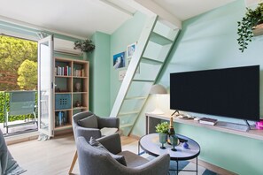 Un salon moderne avec un canapé, un téléviseur, une bibliothèque et une échelle.