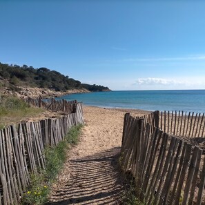 A sandy beach with a wooden fence leading to the water.
