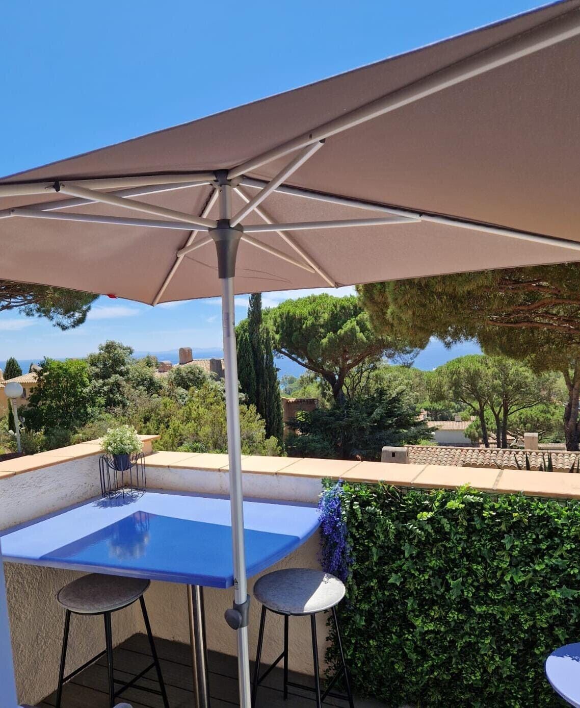 An outdoor patio with a table and chairs, a large umbrella, and a view of the surrounding landscape.