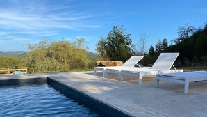 Un espace aménagé au bord de la piscine, avec des chaises longues et une vue sur les montagnes.
