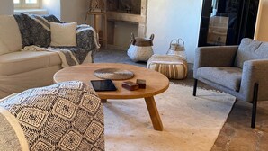 Un salon rustique avec une cheminée en pierre, un canapé, une table basse ronde et un téléviseur.