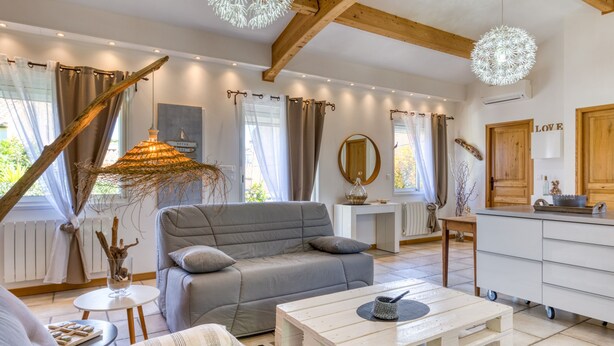 Een moderne woonkamer met een grijze bank, een witte salontafel en een rustiek decoratief object.