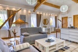 Een moderne woonkamer met een grijze bank, een witte salontafel en een rustiek decoratief object.