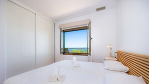 Une chambre d’hôtel avec un lit, une table de chevet, une lampe, une fenêtre donnant sur un paysage agréable et une tête de lit en bois.
