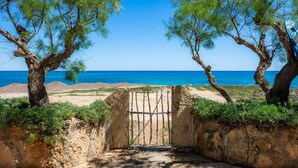 Une vue sur la côte, avec un portail donnant accès à une plage, le tout entouré d’arbres.