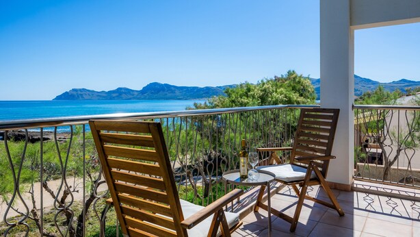 Un balcon avec deux chaises en bois, une petite table ronde et une bouteille de vin.