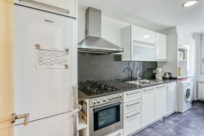 A modern kitchen with a built-in oven, a stove, a sink, and a washing machine. - Apartment 'Georges' with Shared Terrace, Balcony and Air Conditioning (Roses)