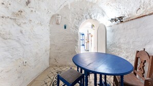 Een kamer met een ronde tafel en stoelen, een vloer met een patroon en een witte muur met structuur.