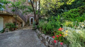 Una scala di pietra che conduce a una porta, circondata da vegetazione lussureggiante e piante fiorite.