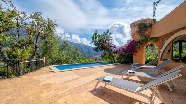 Un espace piscine doté de chaises longues, d’une piscine et offrant une vue sur un paysage montagneux.
