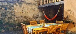 Un espace de restauration extérieur de style rustique, avec un mur en pierre, une table en bois et des chaises.