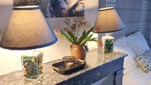 Une chambre d’hôtel avec un lit, deux lampes, un vase de fleurs et un plateau décoratif.