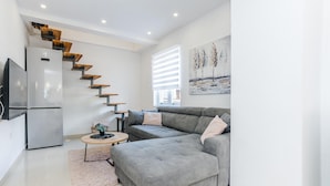 A modern living room with a grey sofa, a wooden staircase, a flat-screen TV, and a painting on the wall. - Beautiful home in Debeljak (Debeljak)