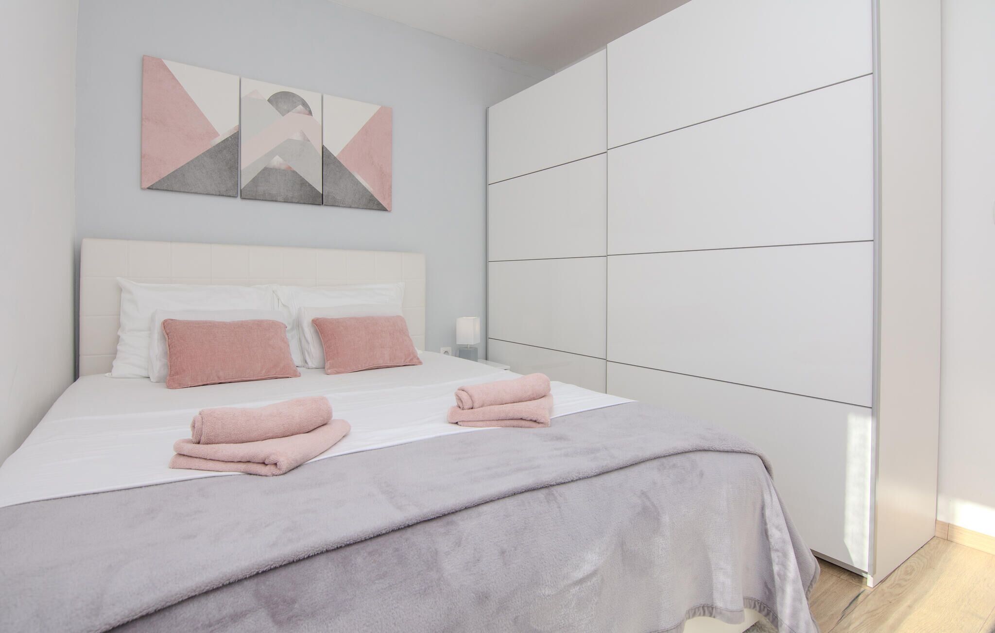 Une chambre à coucher moderne avec un lit, des oreillers et une grande armoire.