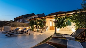A patio with sun loungers and a dining area, a stone wall, and a wooden pergola with hanging plants. - Beautiful home in Debeljak (Debeljak)