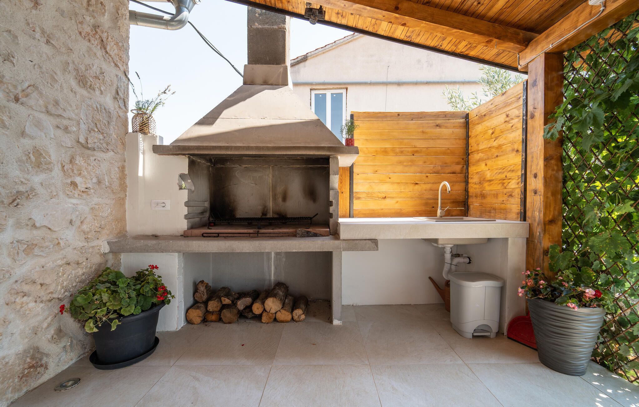 Un espace cuisine extérieur comprenant un barbecue encastré, un évier et un mur en bois.