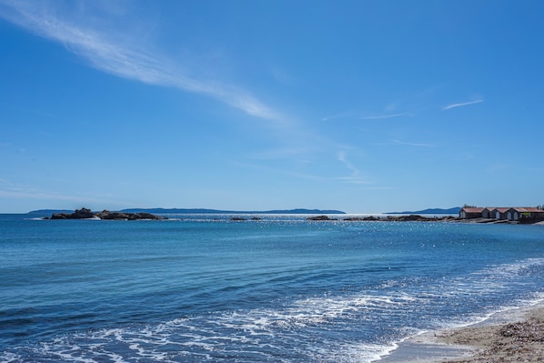 A coastal view with clear skies, calm water, and distant buildings.