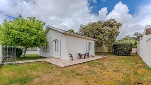 A small house with a patio, a tree, and a bush. - Villa 'Bikini' with Private Terrace and Private Garden (Soulac-sur-Mer)