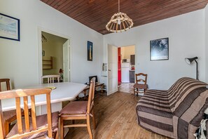 Un comedor con una mesa y sillas de madera, un sofá y una lámpara colgante.