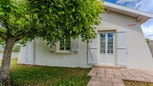 A building with a white exterior, a tree in front, and a paved entrance. - Villa 'Bikini' with Private Terrace and Private Garden (Soulac-sur-Mer)