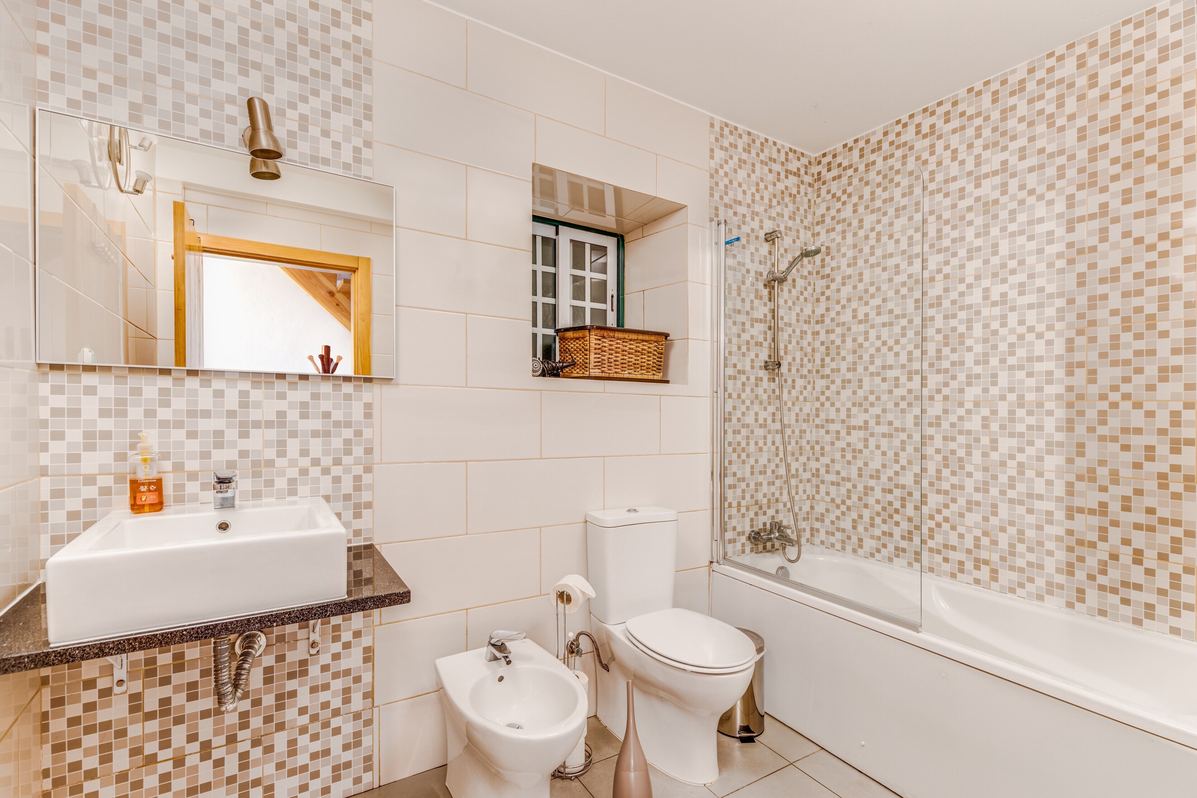 Een badkamer met een wastafel, toilet, bad en bidet.