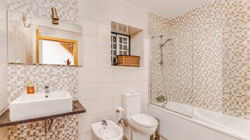 Een badkamer met een wastafel, toilet, bad en bidet.