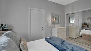 A bedroom with a bed, bedside table, dresser, and a mirror. - Stunning 2/2 dream beach getaway in Surfside (Surfside)