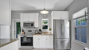 A modern kitchen with white cabinets, stainless steel appliances, a built-in oven, and a large refrigerator. - Stunning 2/2 dream beach getaway in Surfside (Surfside)