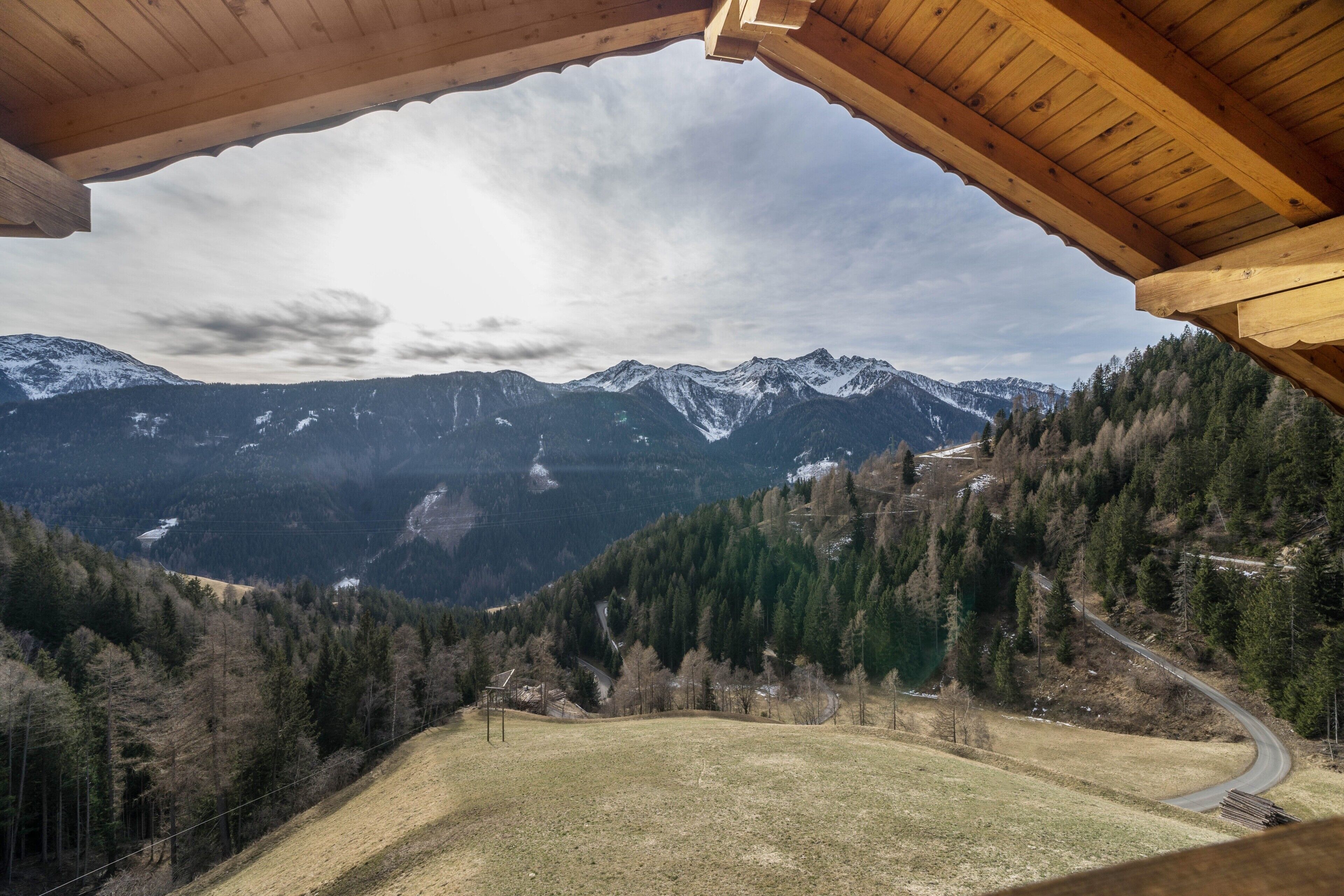 A mountain view from a wooden cabin with a clear sky.