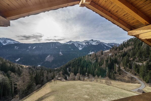 A mountain view from a wooden cabin with a clear sky.