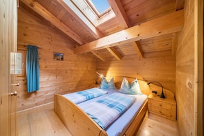 A wooden cabin bedroom with a bed, nightstand, and a skylight. - Apartment 'Thalhof Kornigl' with Mountain View, Shared Garden and Wi-Fi (Ultental BZ)
