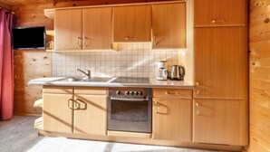Uma cozinha com armários de madeira, um forno de aço inoxidável, uma cafeteira e uma TV de tela plana presa na parede.