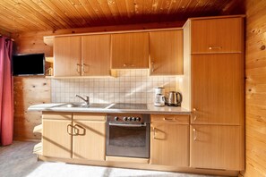 Una cocina con armarios de madera, un horno de acero inoxidable, una cafetera y un televisor de pantalla plana montado en la pared.