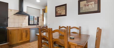 Une cuisine avec des meubles de rangement en bois, une cuisinière et une table à manger avec des chaises.