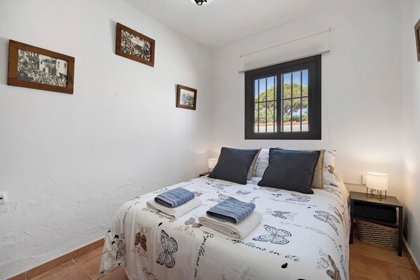 A bedroom with a bed, two pillows, a window, and two framed pictures on the wall.