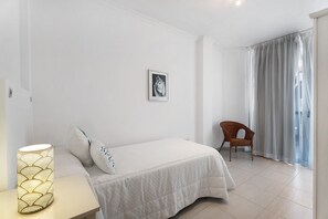 Une chambre à coucher avec un lit, une chaise, une lampe et un tableau au mur.