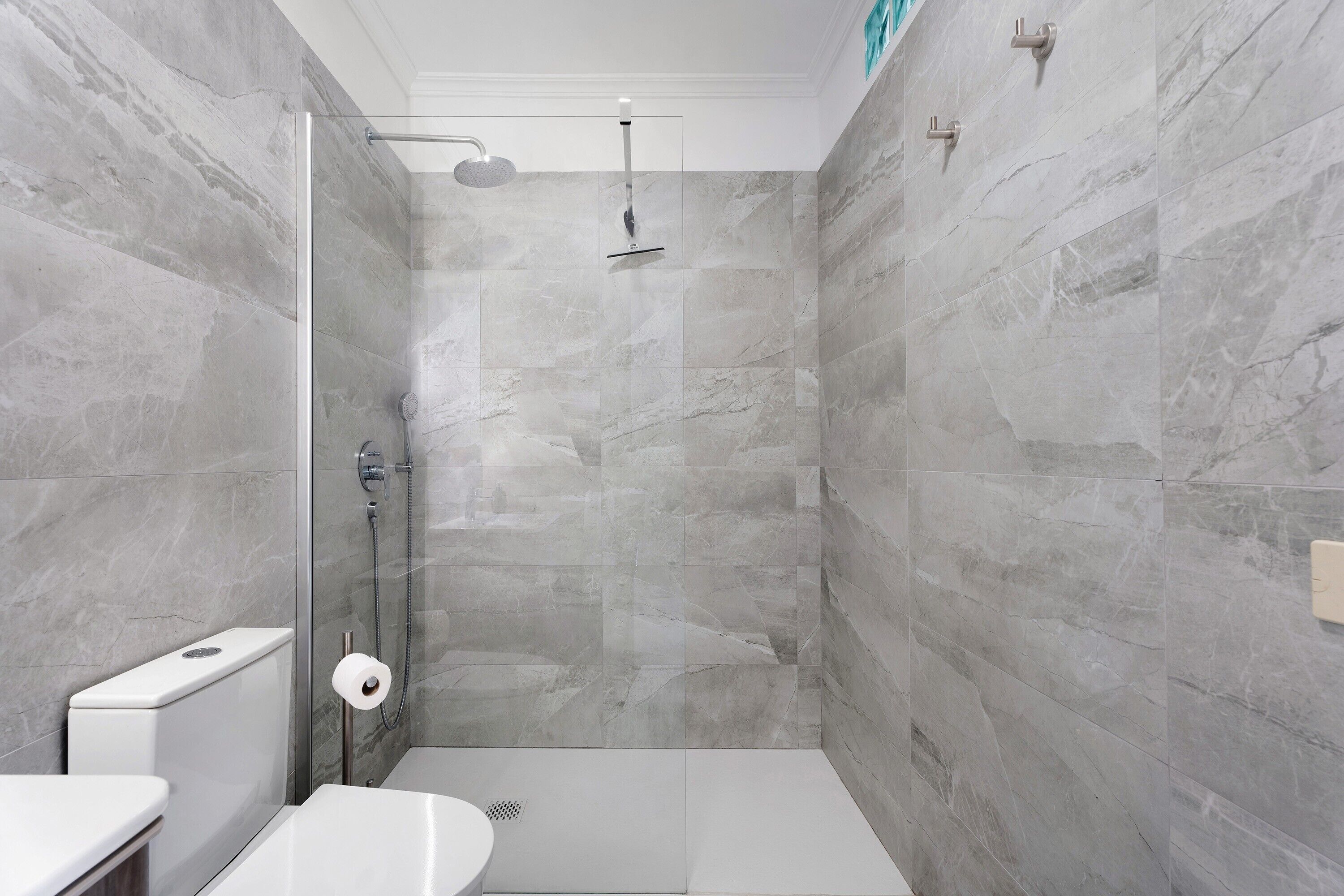 Een moderne badkamer met douche, toilet en wastafel.