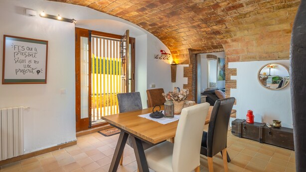 A dining area with a wooden table, chairs, a lantern, and a mirror on the wall.