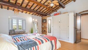 A bedroom with a bed, a television, a wardrobe, and a ceiling fan.
