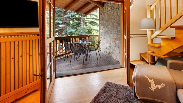 Un interno in legno con una TV, un balcone con tavolo e sedie e una scala.
