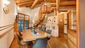 Un tavolo da pranzo in legno con sedie, una scala e un frigorifero in un ambiente accogliente.