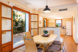 A dining area with a table, chairs, a hanging light fixture, and a view through a glass door. - 'Cala Pi One' with Private Terrace, Wi-Fi and Air Conditioning (Cala Pi)