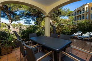 An outdoor patio with a table and chairs, surrounded by greenery and a building in the background. - 'Cala Pi One' with Private Terrace, Wi-Fi and Air Conditioning (Cala Pi)