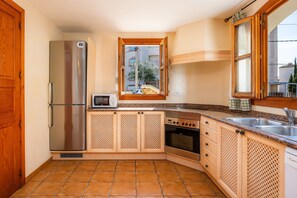 A kitchen with a refrigerator, microwave, oven, and sink.