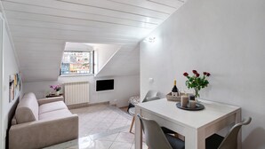 A modern interior with a dining area, sofa, and a view through a skylight.