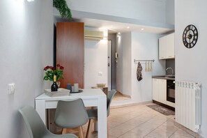 A modern kitchen with white cabinets, a clock, and a dining area with a table and chairs. - Holiday Apartment 'Casa Intimissima' with Air Conditioning (Imperia)